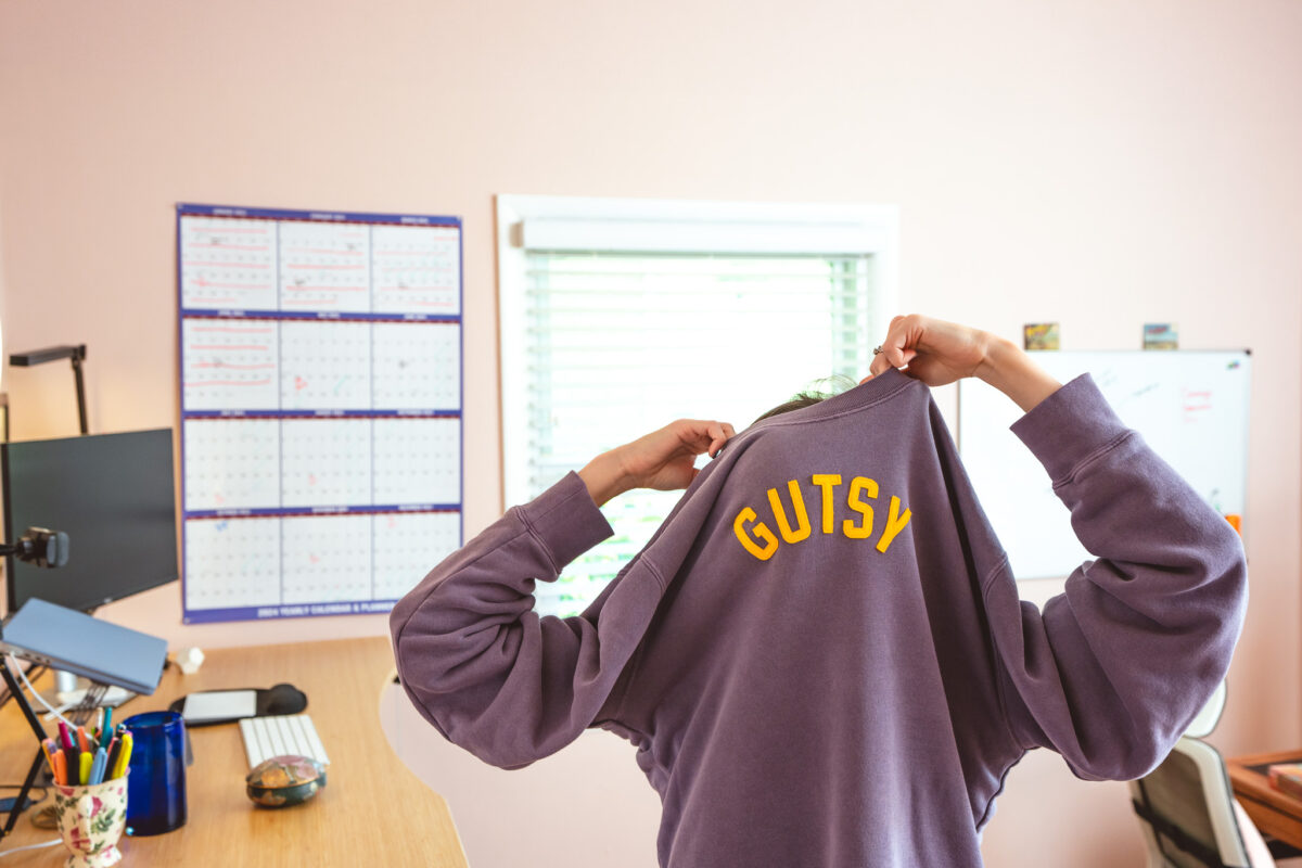 Photo of copywriter Cassie pulling on her "gutsy" sweatshirt and getting stuck